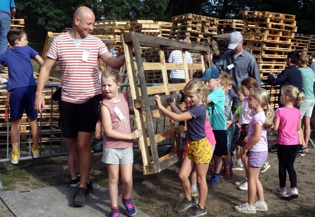 Sterke mannen helpen in Liempde een handje om zware pallets te dragen. 