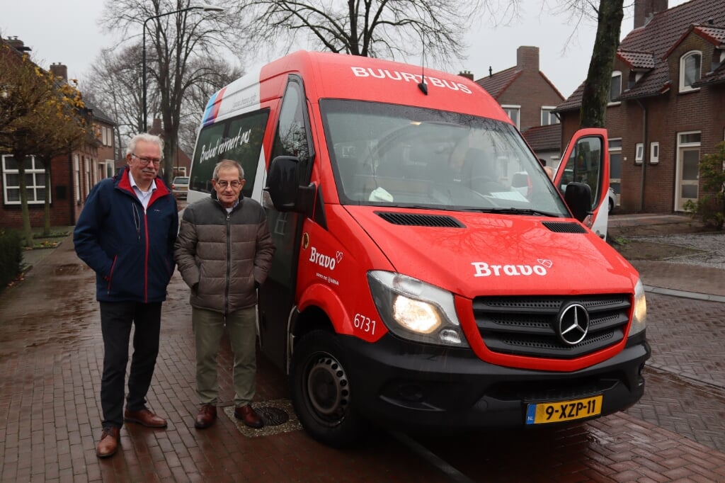 Chauffeurs Tiny van Houtum (links) en Carlo Vlassak poseren bij Buurtbus 203 nabij Ons Café aan de Leunisdijk in Esch. Buurtbusvereniging Esch e.o. bestaat deze maand precies dertig jaar.