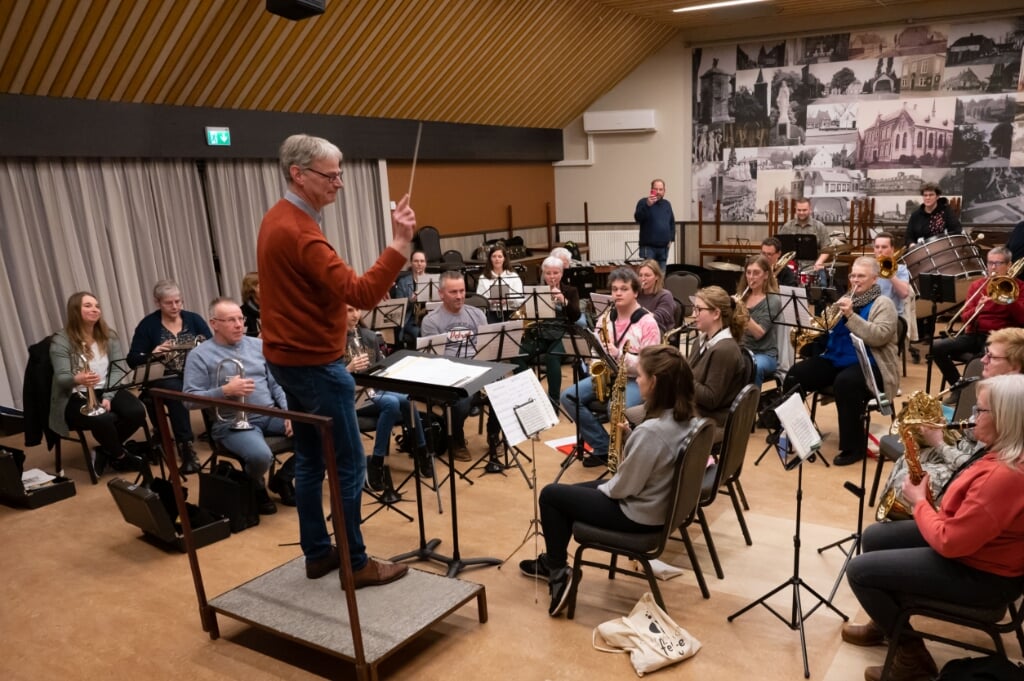 Hans van Bussel oefent zijn muziekstuk met orkest. Zijn concurrent Rick van de Ven staat achterin alvast foto's en filmpjes te maken, waarschijnlijk voor de technische analyse...