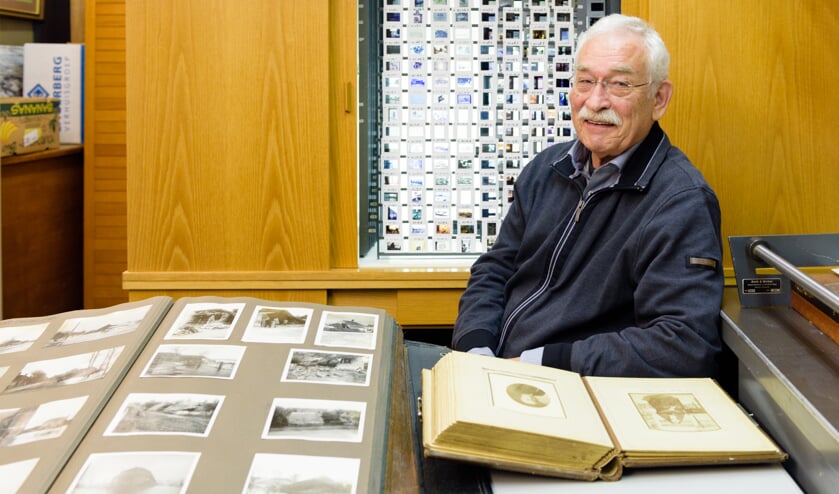 Guus van Heck met links het boek met foto's van de Watersnood van 1926 in Dreumel, en achter hem de kast met dia's.