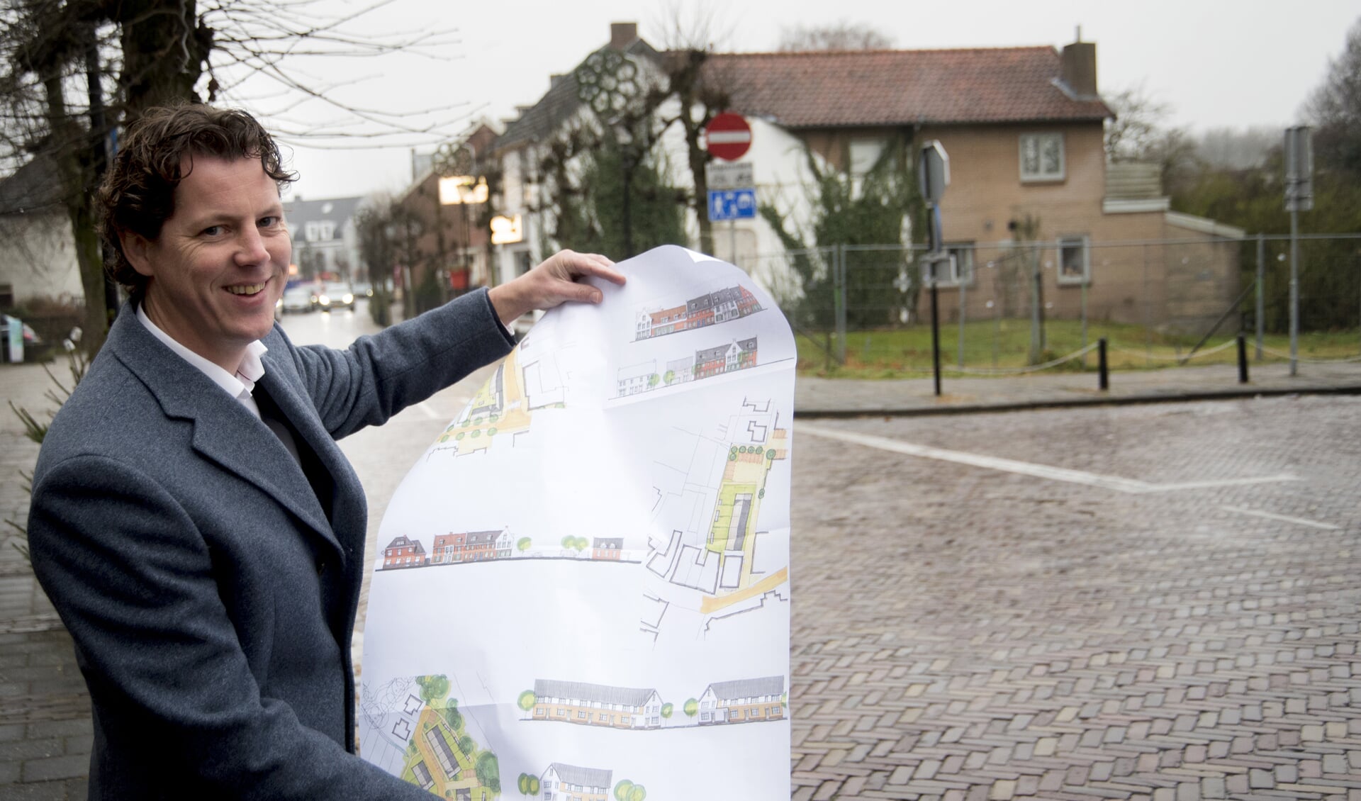 Marco Leenders met tekeningen van de nieuwe woningbouwprojecten, met op de achtergrond 't Smidje.