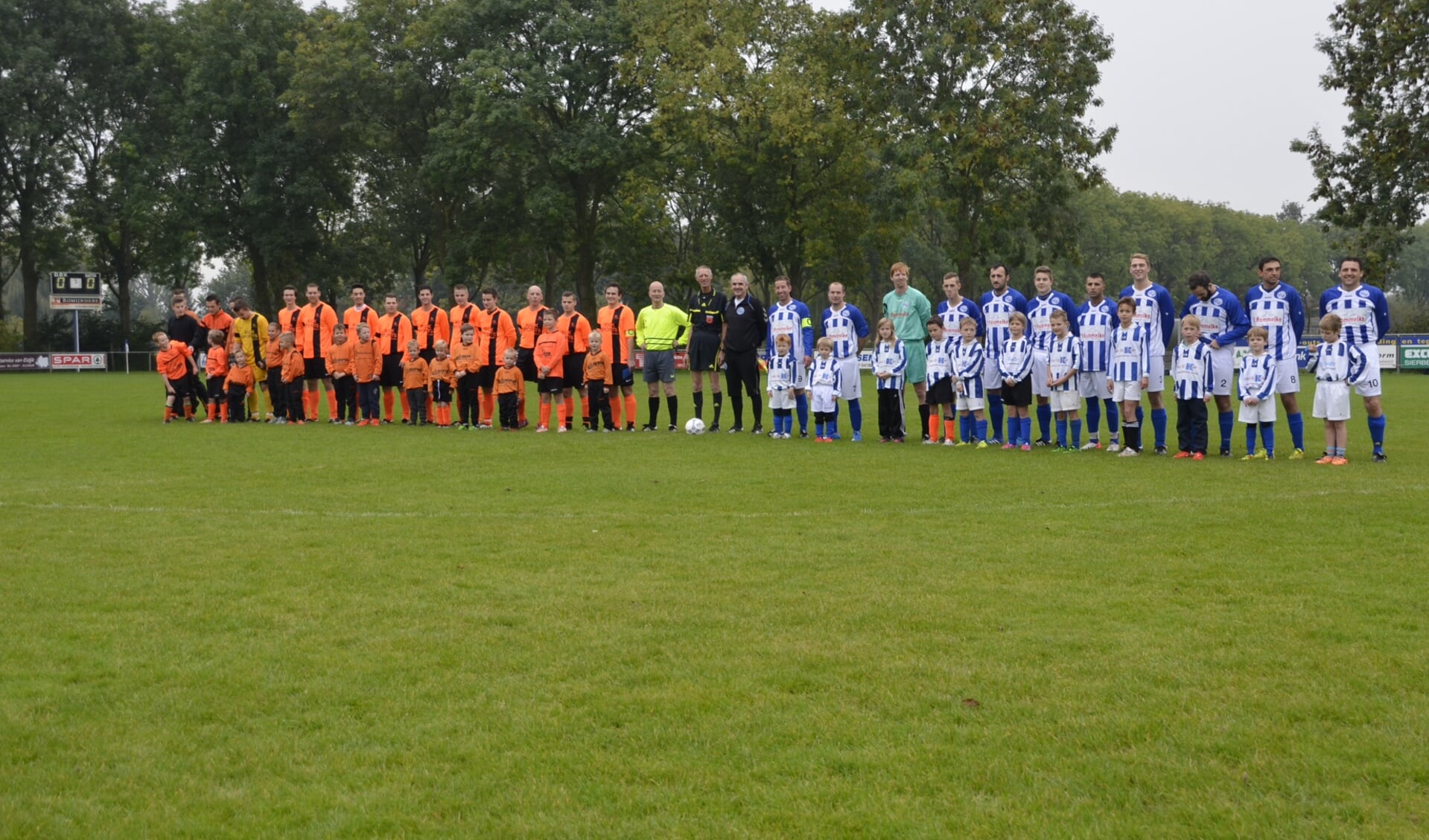 Spelers van Avios (in oranje) en DBV en jeugdspelers en scheidsrechter Adrie van Hoften.