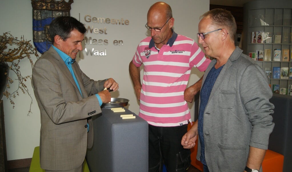 Onder toeziend oog van de commissieleden Jos van Kerkhof (rechts) en Bert van Elk (midden) verricht wethouder sportzaken Ton de Vree de loting. 