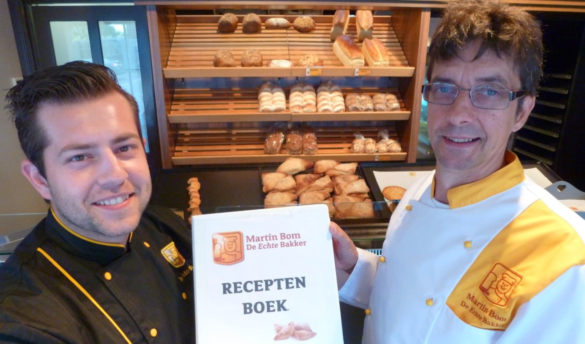 Met het overhandigen van het receptenboek draagt Martin Bom [R] symbolisch zijn bakkerij over aan Jelle Thomassen