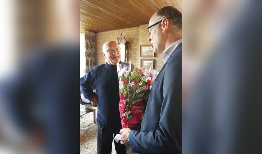 De heer Van Toor is verrast dat wethouder Geert Hendriks hem een bloemetje komt brengen.