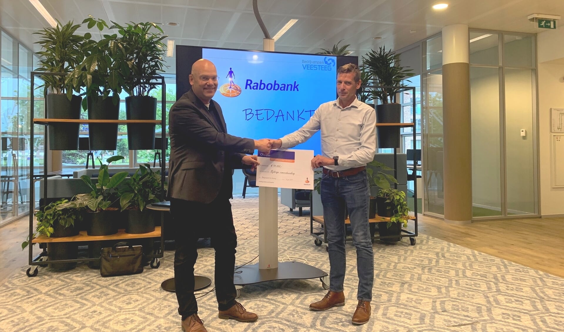 Cheque overhandiging van €10.000,- vuit handen van accountmanager MKB Paul Thonen van de Rabobank aan Kees Willems van camera werkgroep van Bedrijvenpark Veesteeg. 