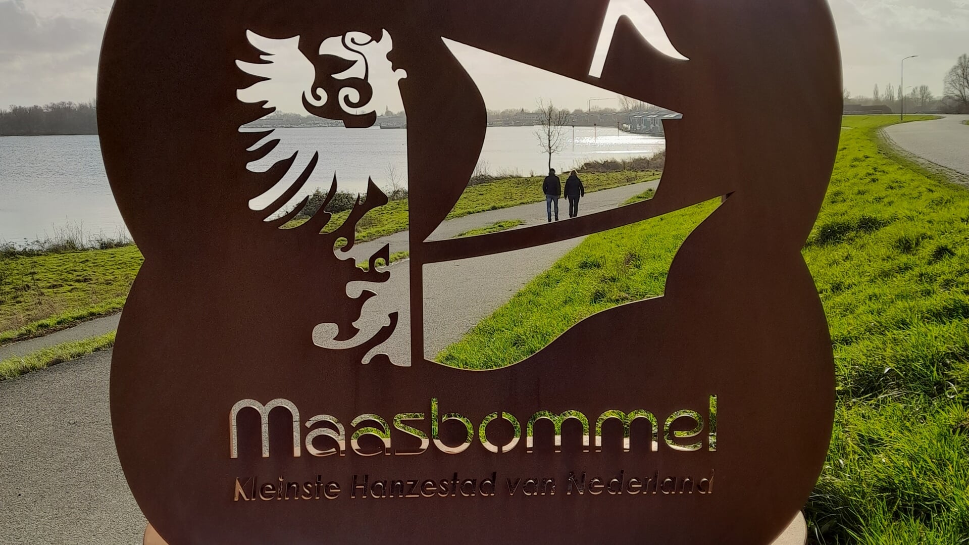 Wandelaars lopen door het logo van Maasbommel