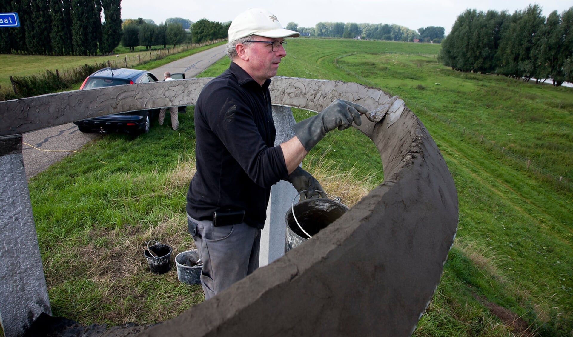 Kunstenaar Cor Litjens restaureert het kunstwerk De Dijk in Weurt.
