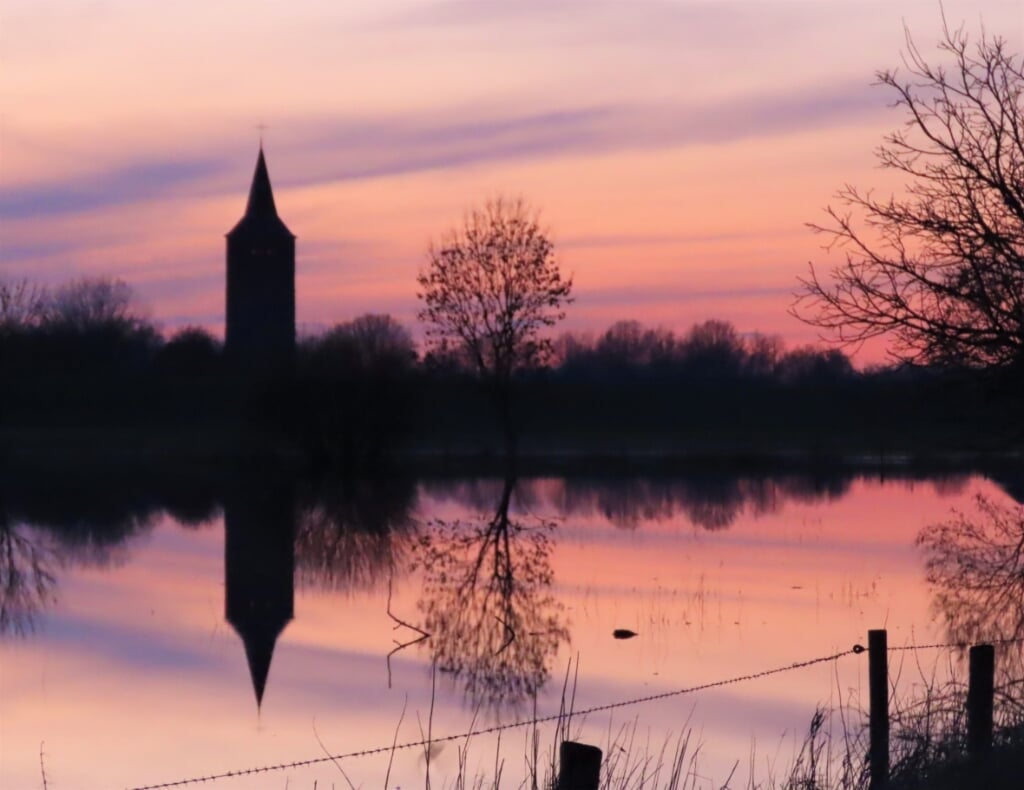 Kerktoren van Winssen bij hoogwater en zonsondergang,