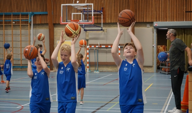 <p>Pieterse (r) houdt deze jonge basketballers scherp.</p>