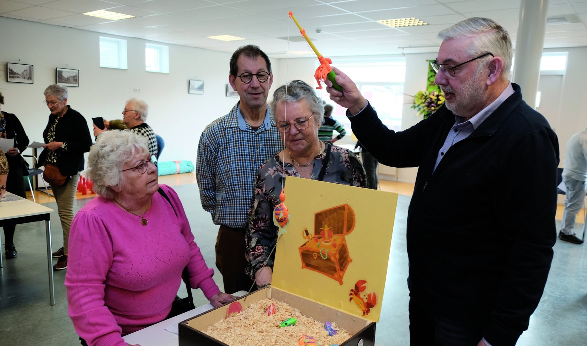 Activiteitenorganisator Piet Vriens toont deelnemers aan de Oud-Hollandse Spelochtend hoe een van de spelletjes moet worden gespeeld.