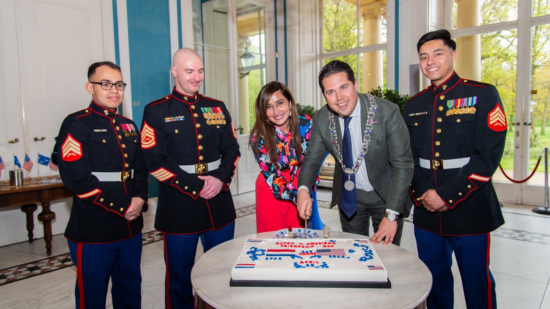 Locoburgemeester Laurens van Doeveren ontving vrijdag 19 april VS-ambassadrice Shefali Razdan Duggal om 242 jaar ononderbroken vriendschap te vieren tussen Nederland en de Verenigde Staten. Op de foto snijden zij samen de taart aan onder toeziend oog van Amerikaanse mariniers. Foto: Patrick Kop.
