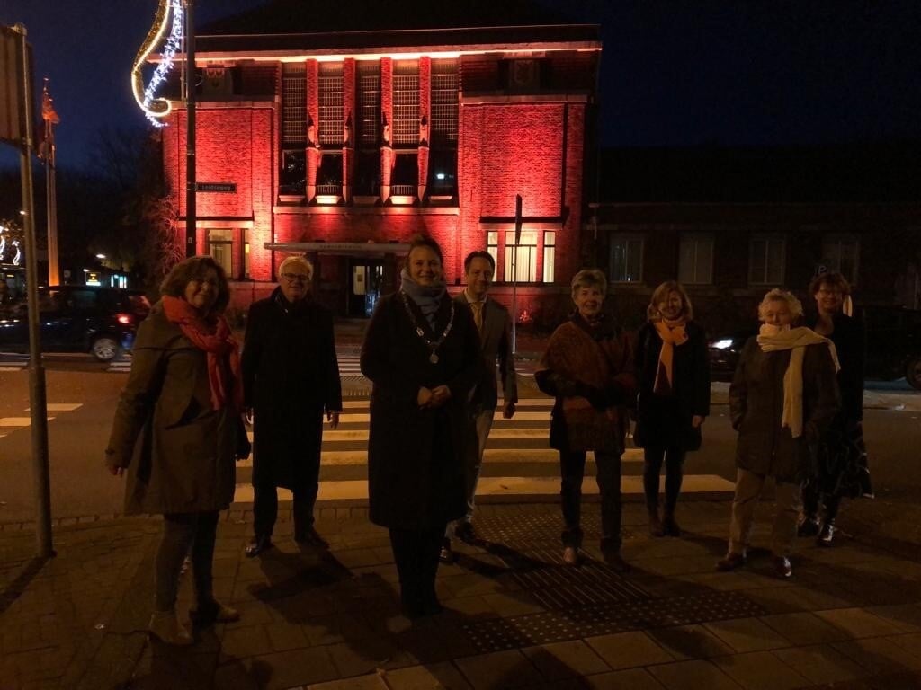 De burgemeester en wethouders van Voorschoten staan samen met de leden van de Soroptimistclub Wassenaar/Voorschoten voor het oranje gekleurde gemeentehuis. Foto: PR.