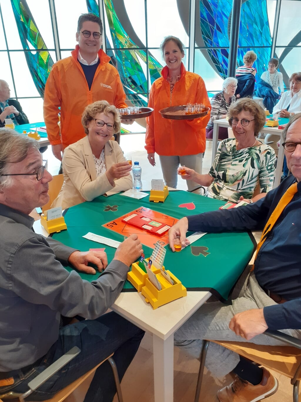Carlijn Gunst en René van Delft delen Oranjebitter uit tijdens het bridgetoernooi.
