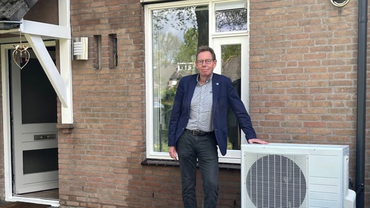 Directeur-bestuurder Hans Vedder bij de buitenunit van een hybride warmtepomp.