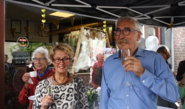 Het echtpaar De Groot proost op het vijftigjarig bestaan van de schoenhersteller in de Nieuwstraat. Bert de Groot was overdonderd door het verrassingsfeest. Foto: Kees Stap