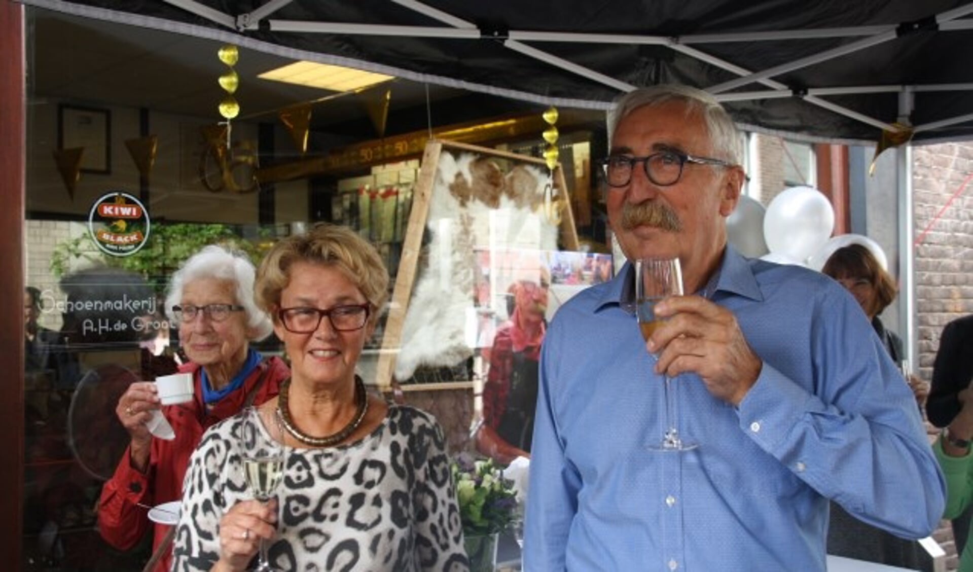 Het echtpaar De Groot proost op het vijftigjarig bestaan van de schoenhersteller in de Nieuwstraat. Bert de Groot was overdonderd door het verrassingsfeest. Foto: Kees Stap