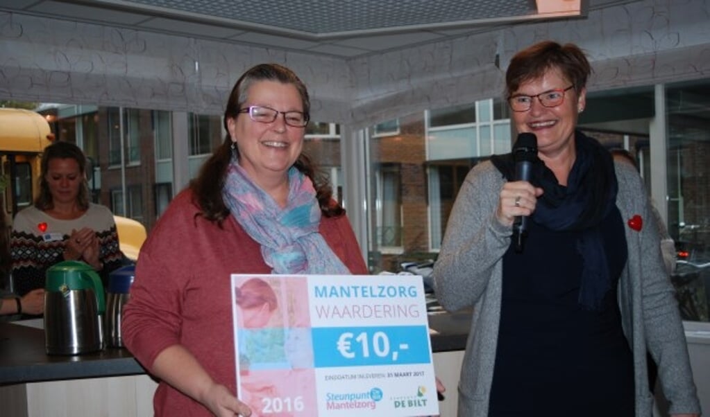 Sybelle van Erven ontvangt uit handen van Anne Brommersma een symbolische cheque van tien euro, een vijfde deel van de Mantelzorgwaardering die alle bij Steunpunt Mantelzorg De Bilt bekende mantelzorgers krijgen.

