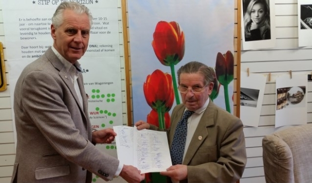 Alois Canters overhandigt de handtekeningen van 74 Wageningse winkeliers aan wethouder Han ter Maat. Canters hoopt de gemeente te overtuigen van de noodzaak van lampen in het midden van de Hoogstraat. Foto: Rick Praamstra