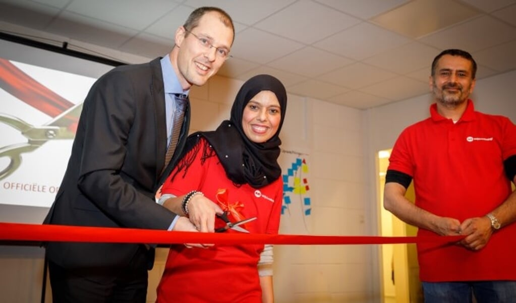 Wethouder Sander Jansen knipt samen met Souad het rode lint door om het WijkLeerbedrijf officieel te openen. FOTO: Martin Smit