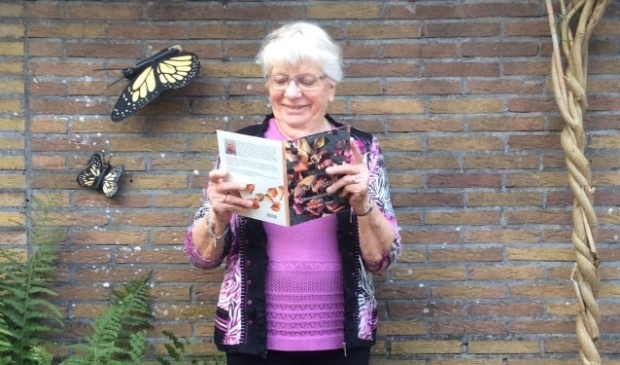 Trots laat Janny de Veer zich fotograferen in haar tuin. Met haar eigen boekje: "Mijn Hoogtijdag, overpeinzin-gen van Janny de Veer"