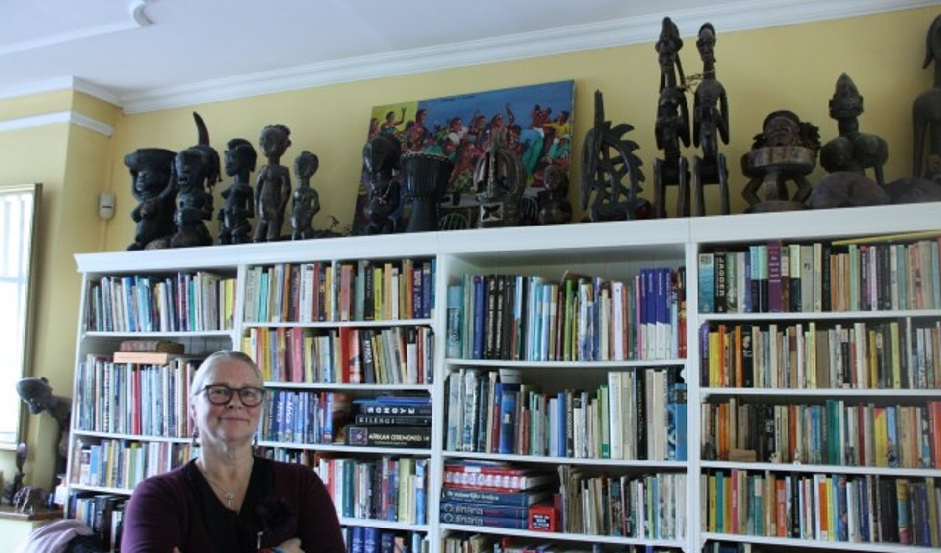 Lucy Geurtsen uit De Bilt voor haar boekenkast vol met boeken en beelden uit Afrika. FOTO: Asta Diepen Stöpler