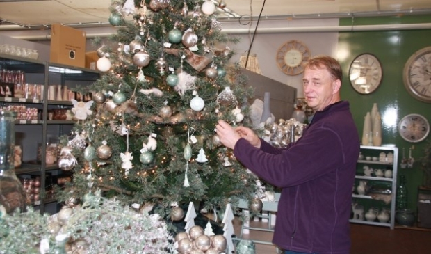 Elo Jansen legt de laatste hand aan een kerstboom op de kerstafdeling bij Tuincentrum De Oude Tol. Groen en zilver zijn belangrijke kleuren die komende winter de overhand gaan krijgen. (foto: Kees Stap)