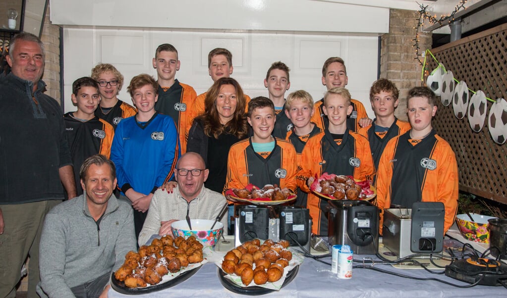 Het MOC jongens tot 15 jaar voetbalteam, met Marlies Meinesz in het midden, bakt de oliebollen bruin.