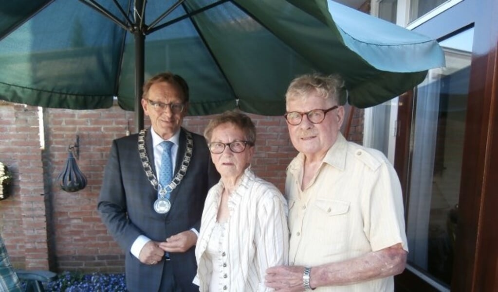 Het echtpaar Van der Palm poseert met burgemeester Janssen onder de parasol. Foto: Marijke Wieringa