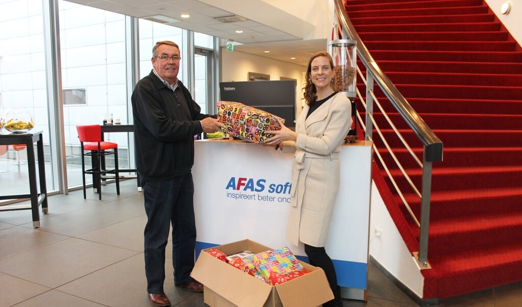 Jeanine Boogaard van AFAS overhandigde de pakjes aan de voorzitter van de Voedselbank Leusden, Henk van de Wolde.