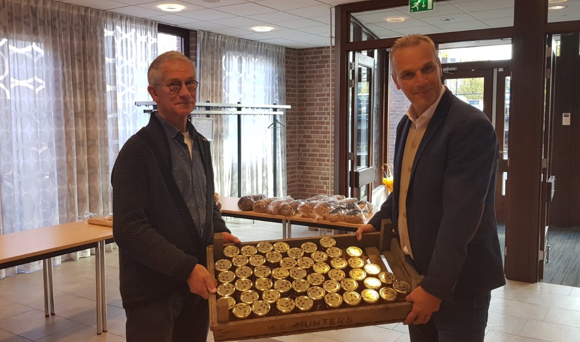 Wethouder Wim Vos overhandigt honing aan een vrijwilliger van voedselbank Leusden