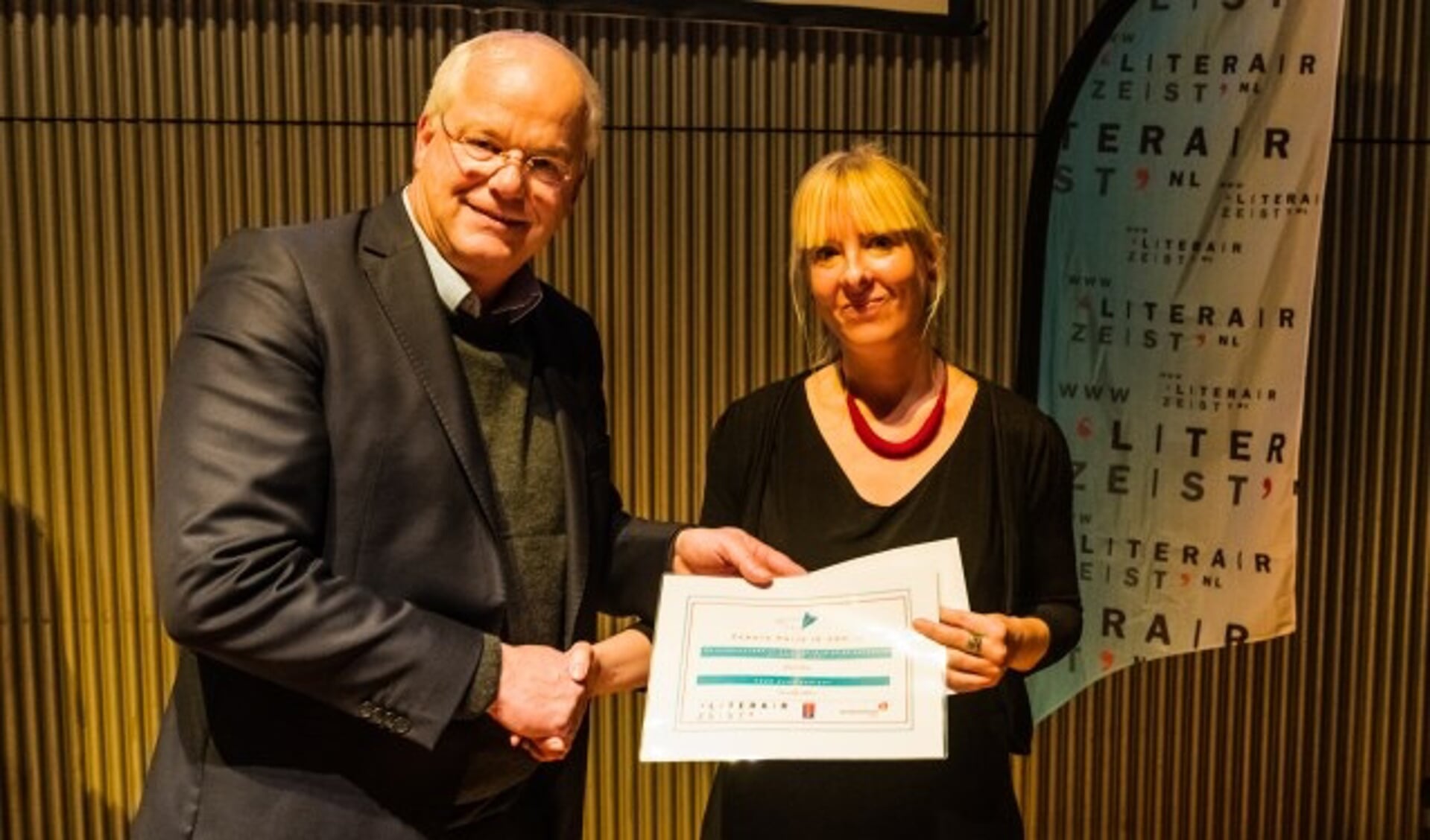 Jan Arns ontvangt de LiteratuurPrijs Zeist uit handen van wethouder Mel Boas op 23 november in De Klinker in Zeist