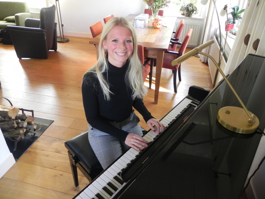 Christien achter de piano in haar ouderlijk huis waar ze zangles geeft aan haar leerlingen.