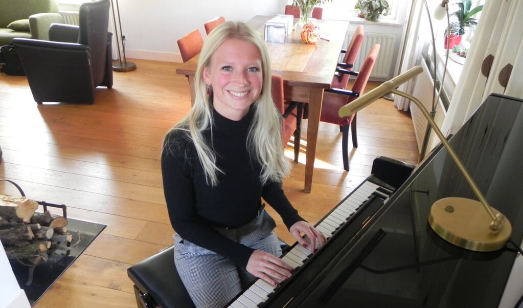 Christien achter de piano in haar ouderlijk huis waar ze zangles geeft aan haar leerlingen. 
