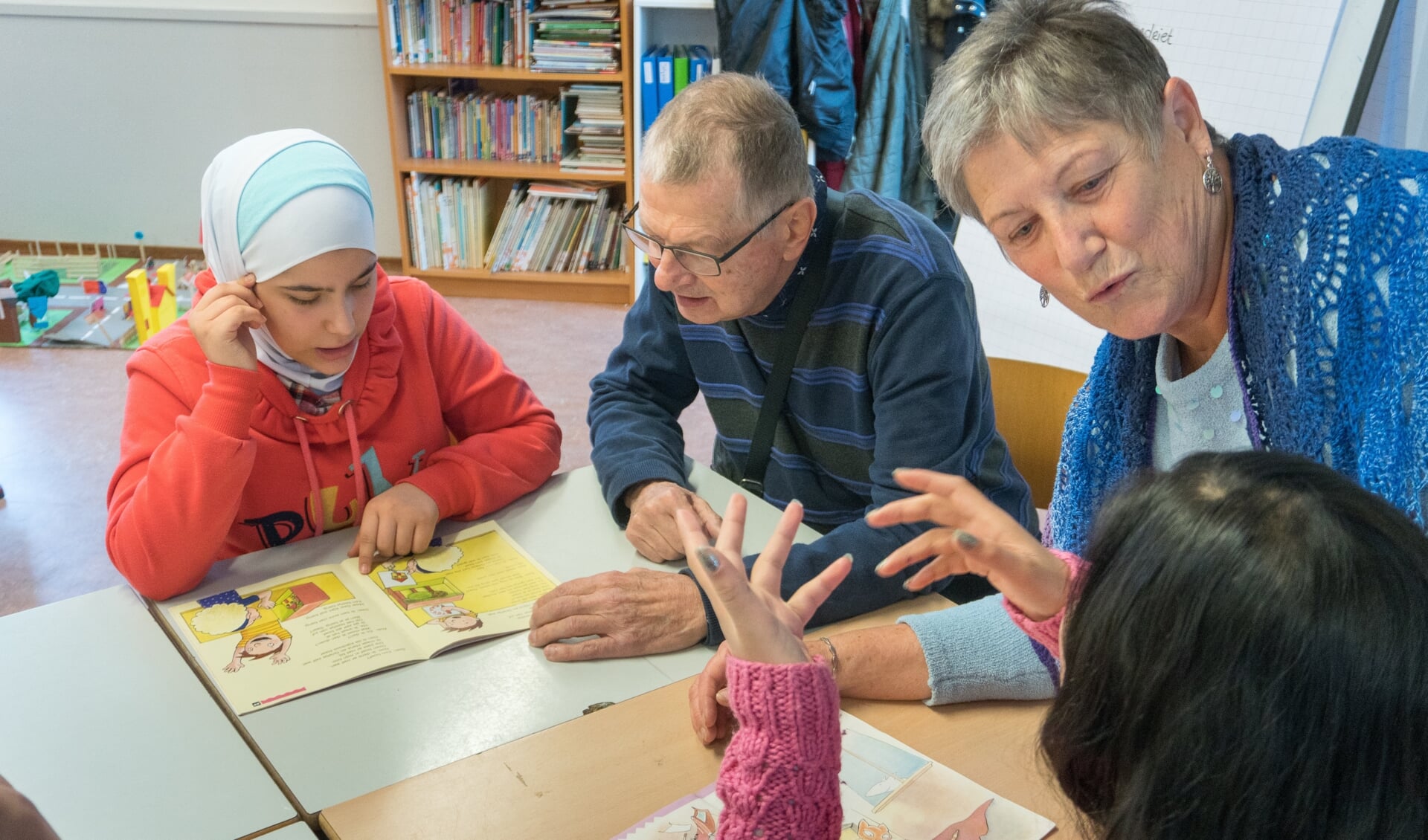 Vrijwilligers Ton(l) en Odette(r) helpen kinderen bij het lezen op de Taalschool in Nieuwland