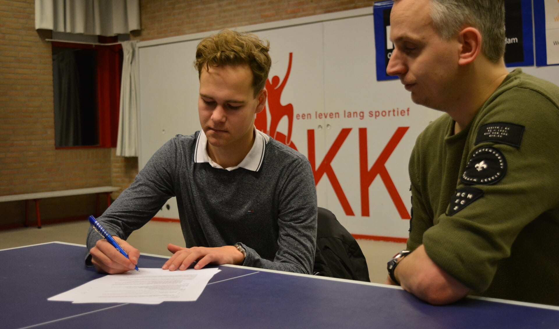 Joël tekent samen met voorzitter Adriaan de overeenkomst