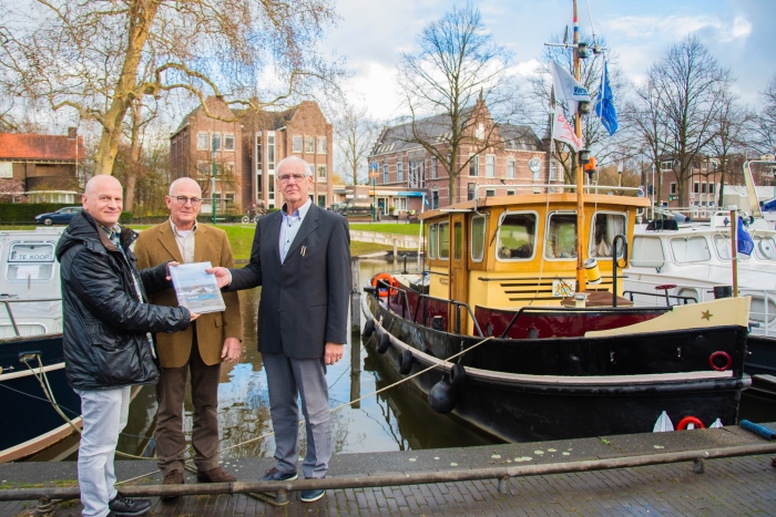 Egbert Egberts (links) overhandigt het eerste exemplaar aan Chris Nieuwpoort (rechts) en Piet van Zaal.