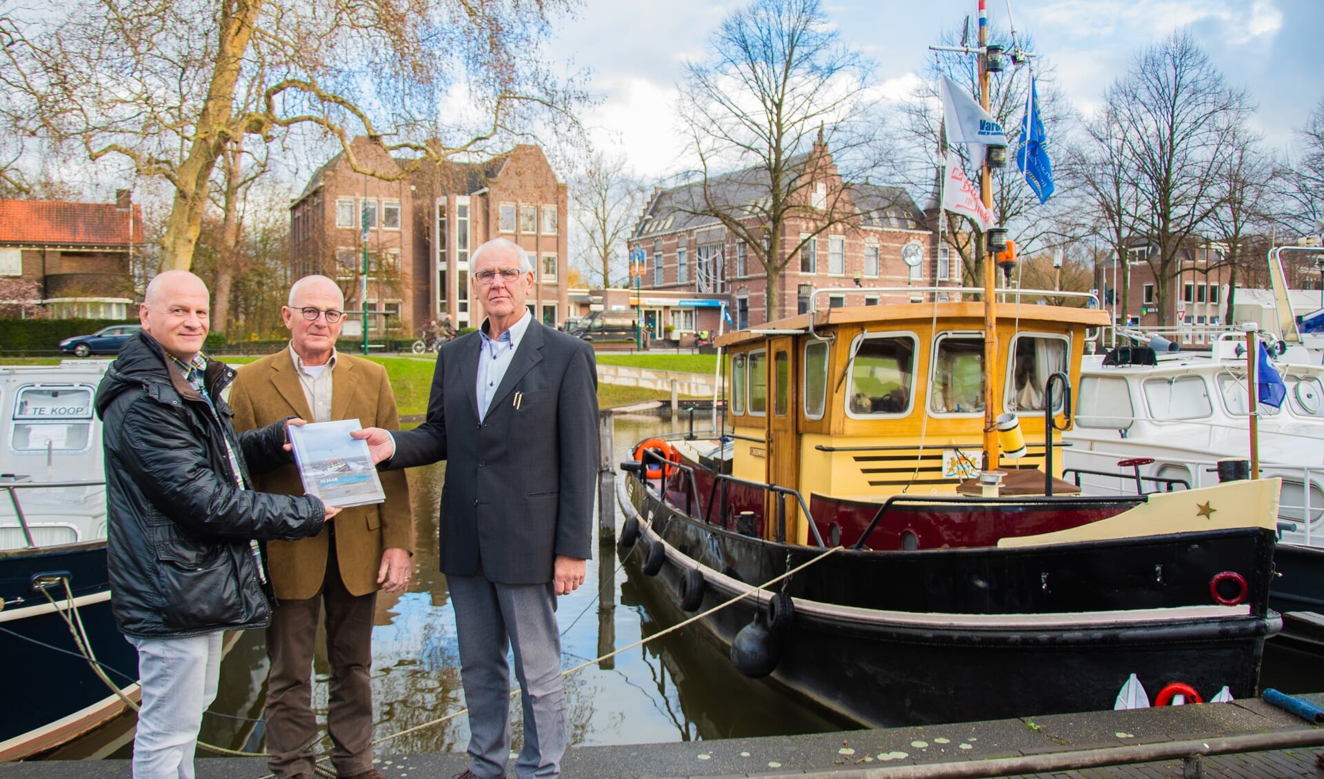 Egbert Egberts (links) overhandigt het eerste exemplaar aan Chris Nieuwpoort (rechts) en Piet van Zaal.