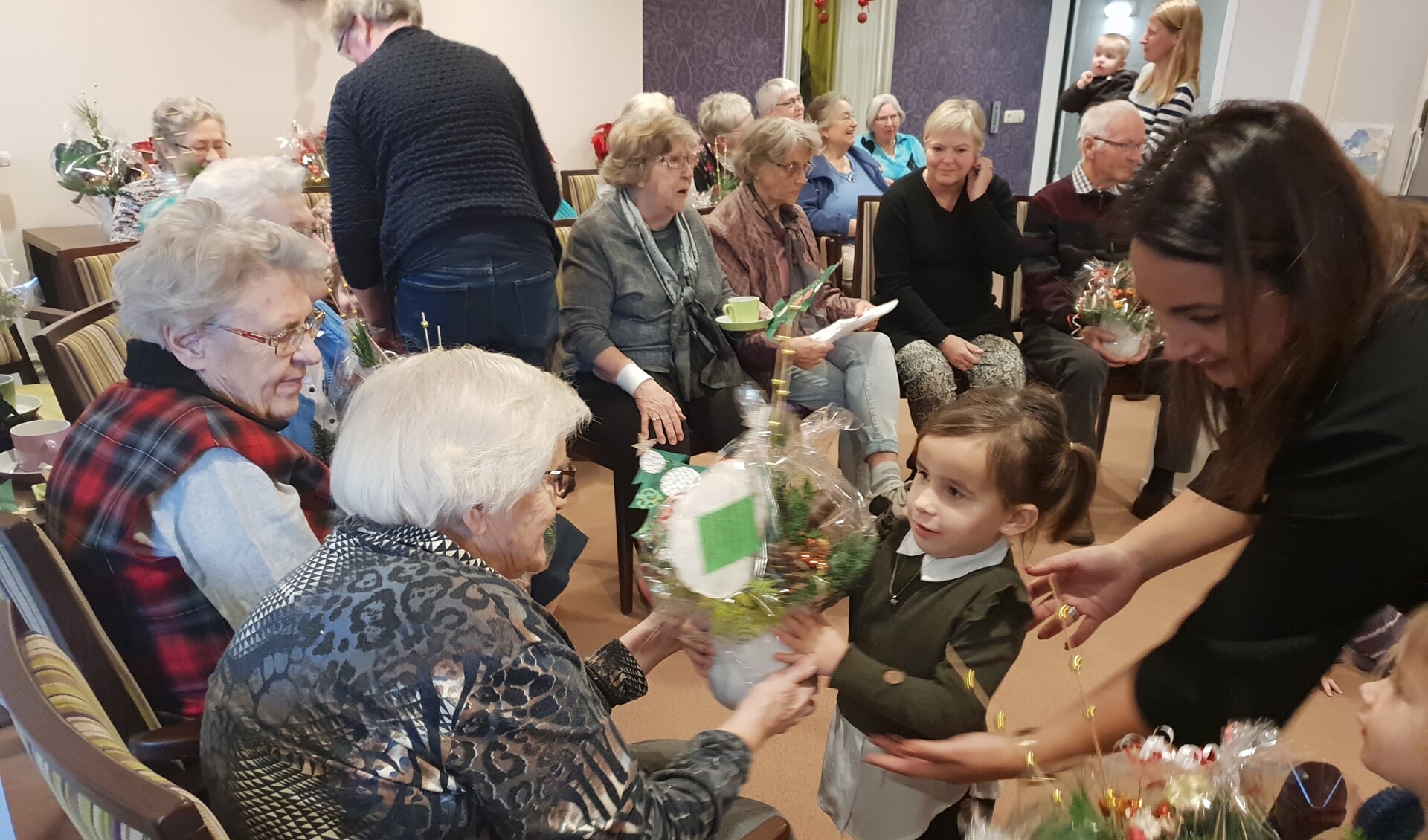 Peuter Klein Vossenhol geeft kerststukje aan bewoner Timanshof