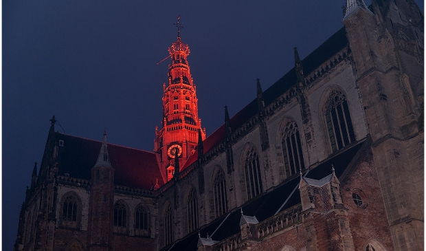 <p>De toren van de Grote of Sint - Bavokerk kleurt oranje.</p>