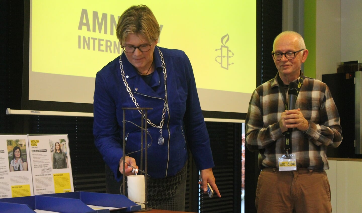 Burgemeester Cnossen en voorzitter Ruud van der Krogt steken de Amnestykaars aan.