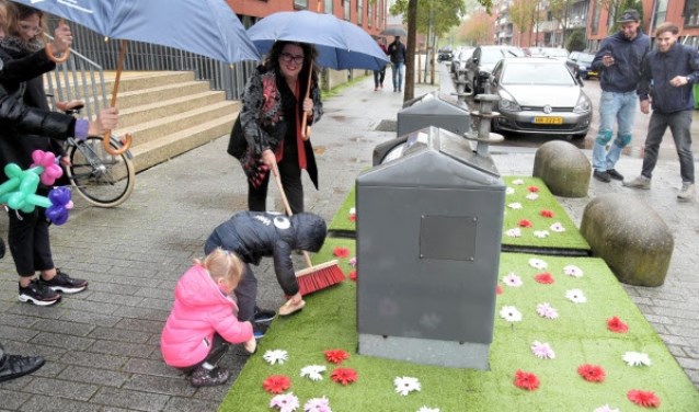 Wethouder Marjolein Steffens-van de Water borstelt samen met buurtkinderen de fleurige matten in Hoofddorp.
