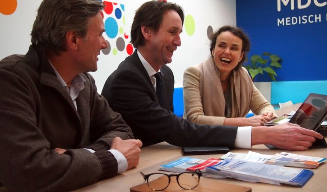 Wethouder Raat bekijkt met Roderik Kraaijenhagen en Sabine Pinedo Vital10 op een tablet.