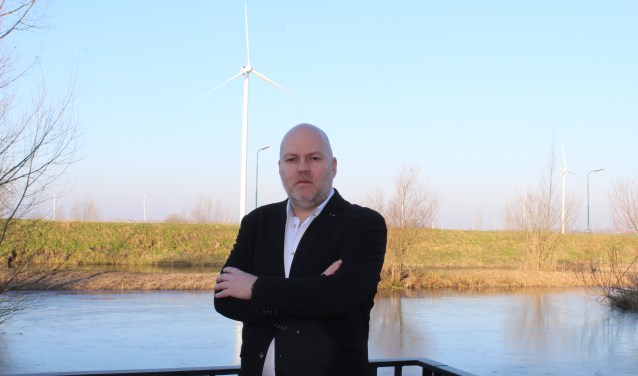 Maurice Bakker voor zijn huis met de windmolen op de achtergrond.
