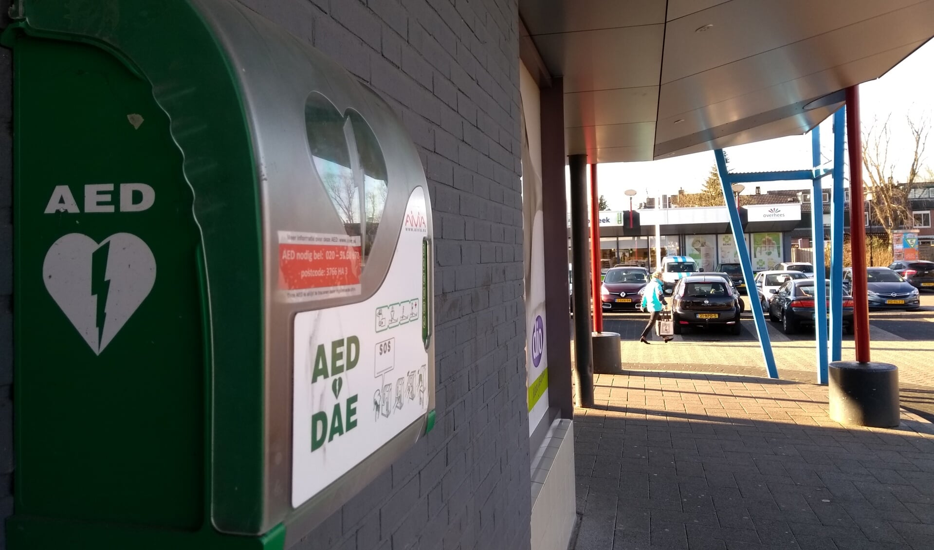 In winkelcentrum Overhees hangt, aan de zijde van de Di Lassostraat,  hangt ee kast met een AED.