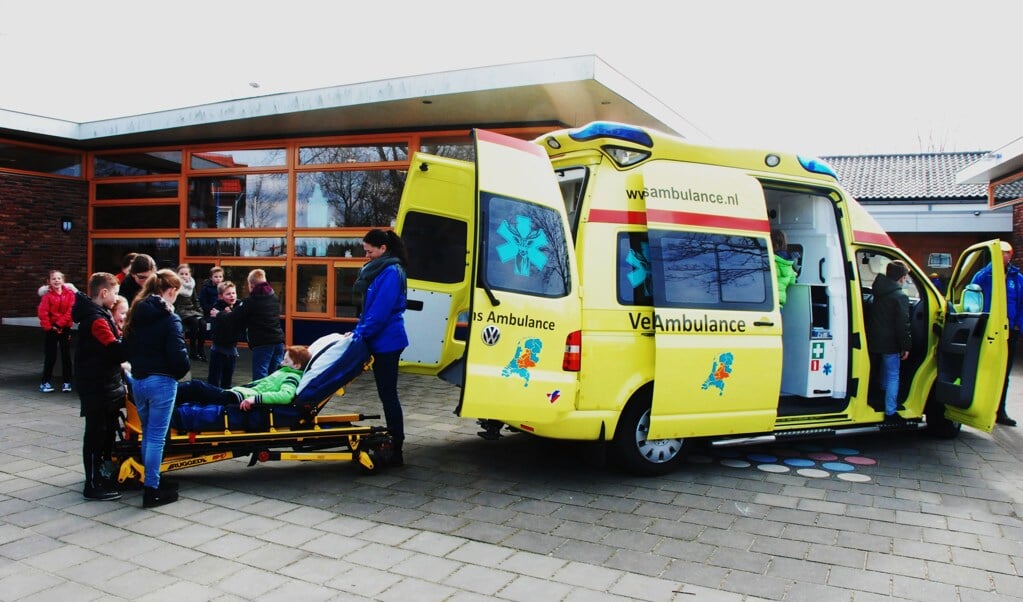 Even de brancard van de Veluwse Wens Ambulance testen, terwijl anderen een kijkje in de auto nemen.