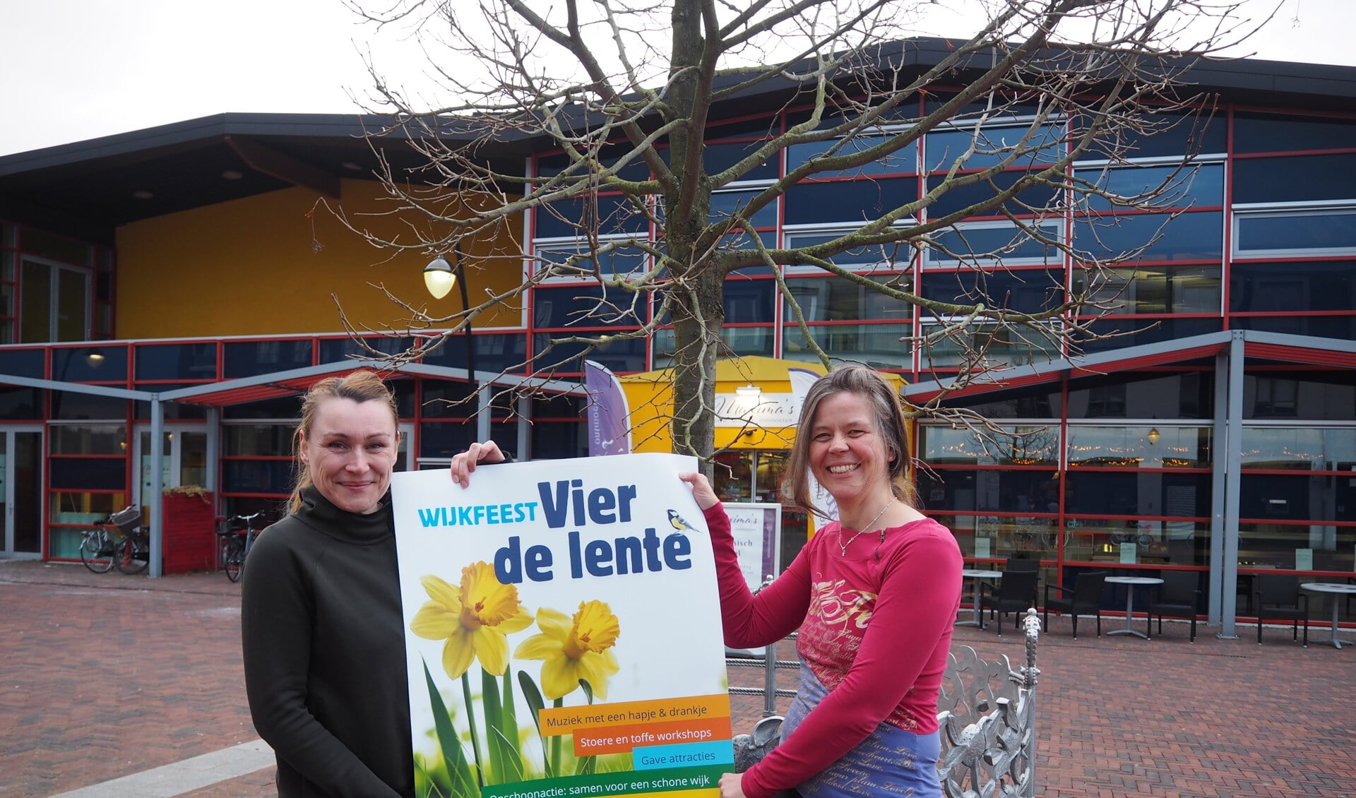 Organisatoren Sara Dirkse-Versteeg en Like van der Ham-van Hulten met een poster van het wijkfeest 'Vier de lente'.