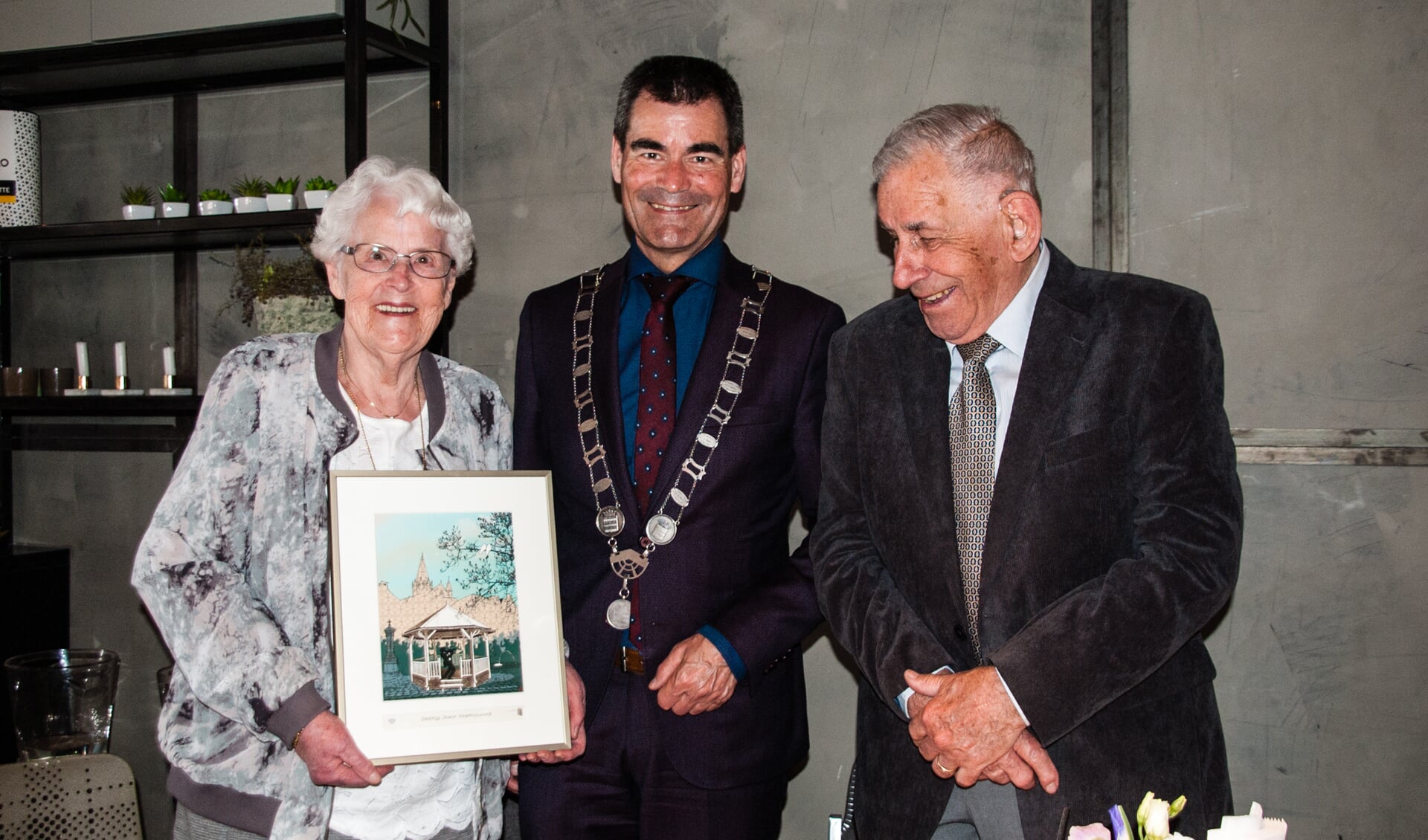 Burgemeester De Jong overhandigt het echtpaar Van Arnhem-Kooijman een mooie herinnering.