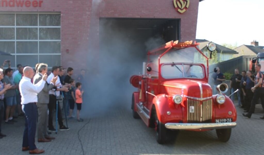 De gerestaureerde brandweer oldtimer verscheen vanuit een dichte rookwolk uit de kazerne aan de Achterbergsestraatweg. De belangstelling voor de fraaie oldtimer was overweldigend. (Foto: Henk Jansen)