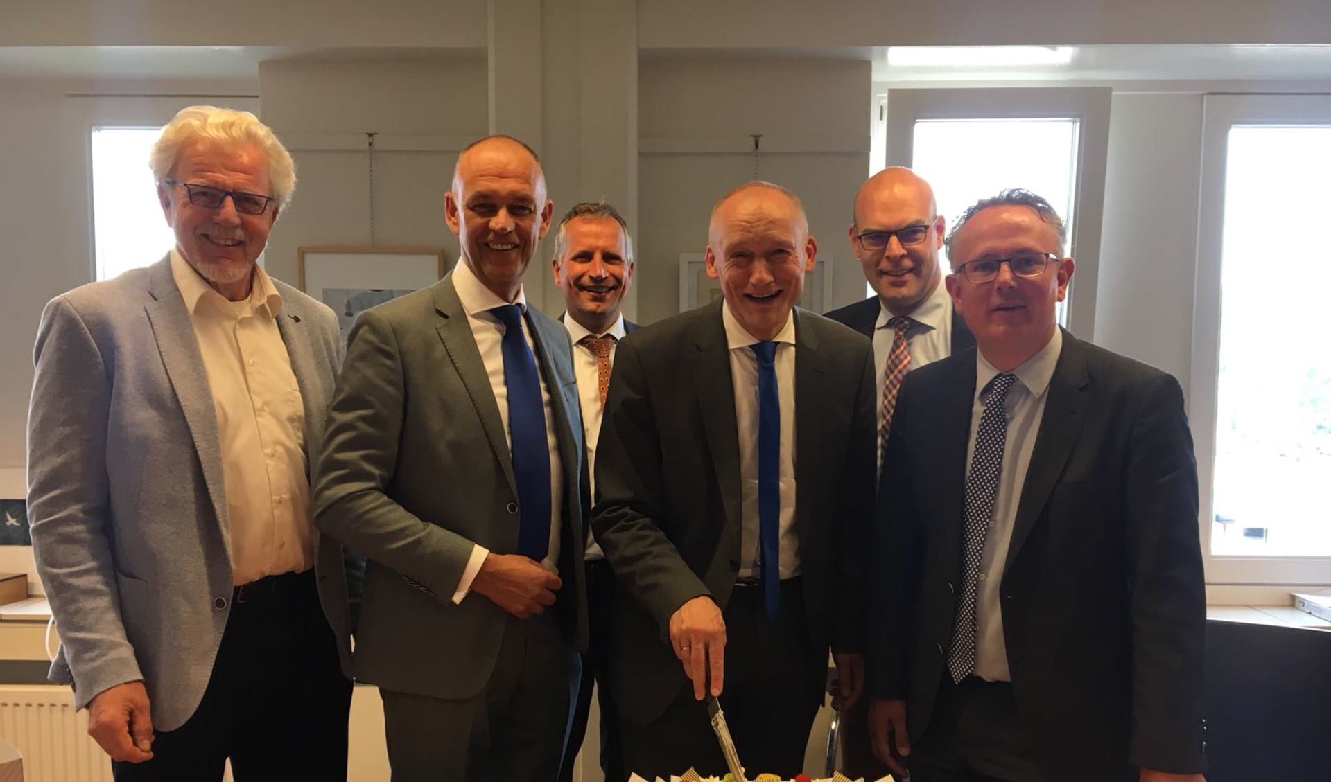 Wethouder Hans Marchal (Wijk bij Duurstede) snijdt de taart aan, met rechts naast hem wethouder Herman Geerdes (Houten)